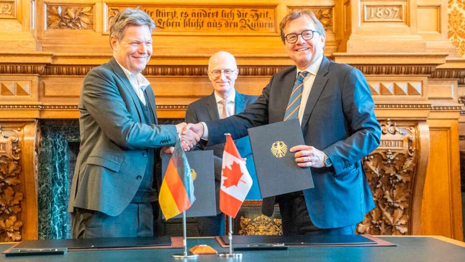 Bundeswirtschaftsminister Robert Habeck (links) und Jonathan Wilkinson, Minister für Energie und natürliche Ressourcen Kanada, unterzeichnen einen Letter of Intent im Beisein von Hamburgs erstem Bürgermeister Peter Tschentscher. 